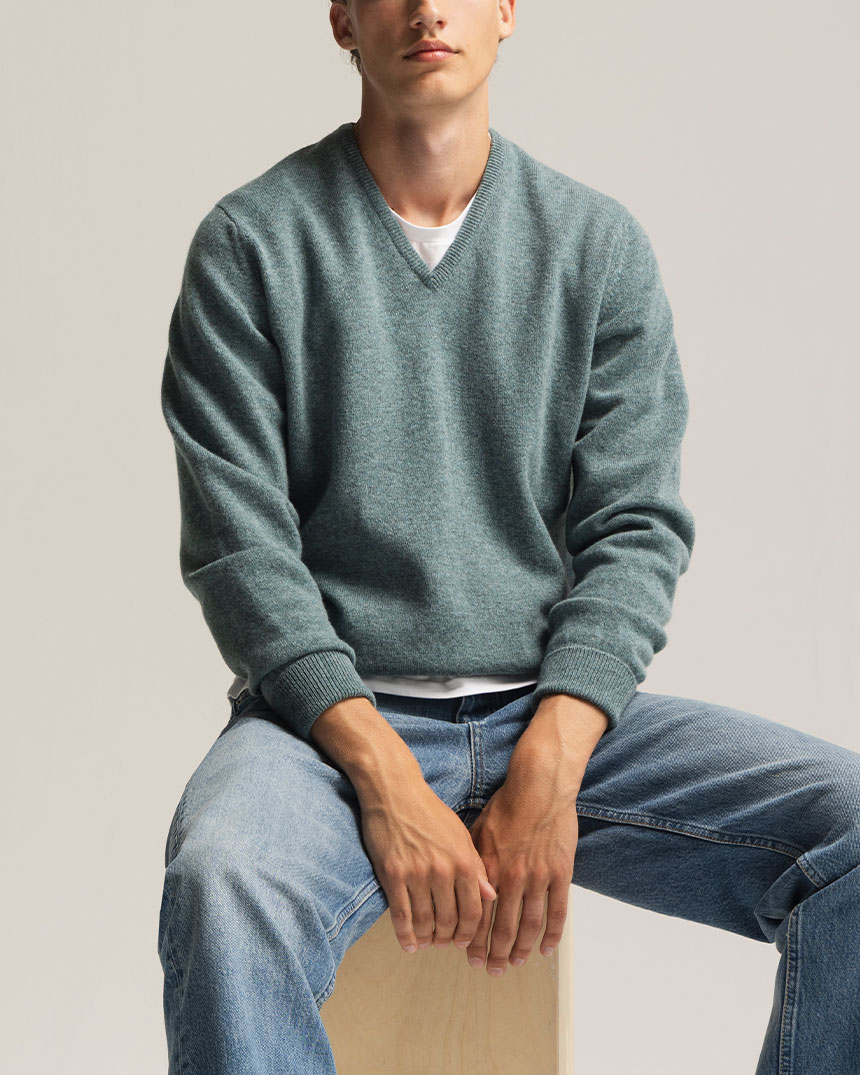 Grüner V-Pullover, blaue Jeans